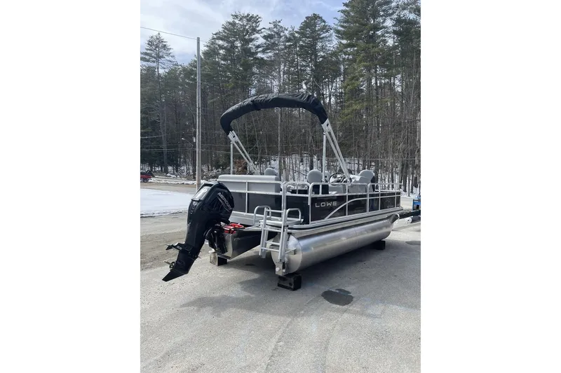 Slide: The Image of 2024 Lowe Ultra 162 Fish & Cruise pontoon boat with outboard motor, parked outdoors. - 2
