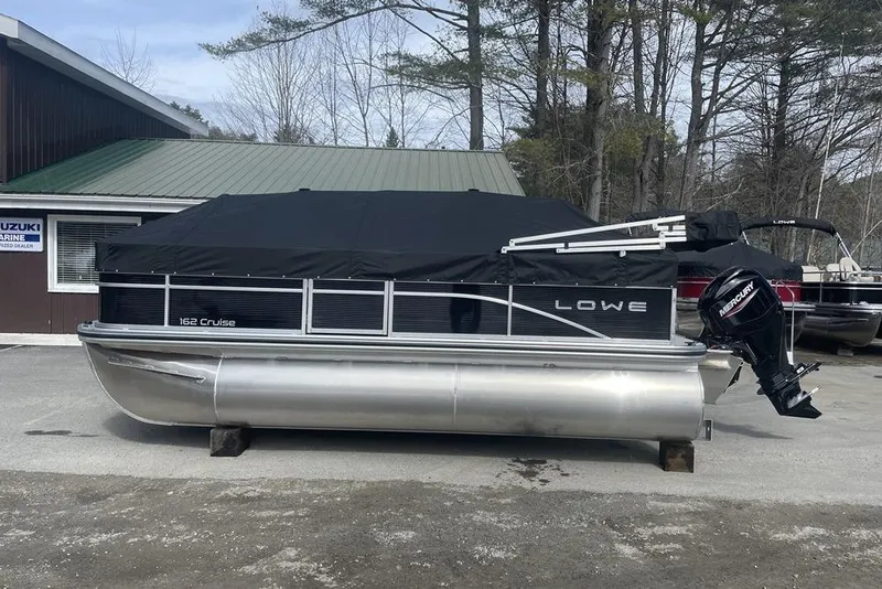 Slide: The Image of 2024 Lowe Ultra 162 Fish & Cruise pontoon boat with Mercury outboard motor, covered and parked. - 5
