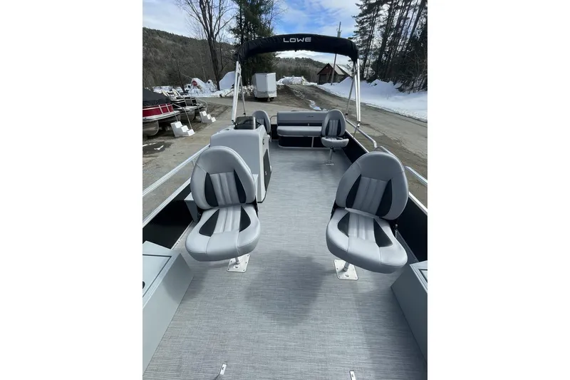 Slide: The Image of 2024 Lowe Ultra 162 Fish & Cruise boat with gray seating and canopy, parked outdoors. - 7