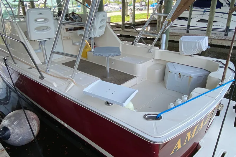 Slide: The Image of 2003 Mainship Pilot 30-II Sedan docked in marina, red hull, sheltered by wooden structure. - 3