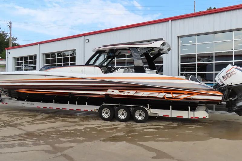 Slide: The Image of 2024 MTI 50v boat on trailer outside a garage, showcasing sleek design and powerful engines. - 4