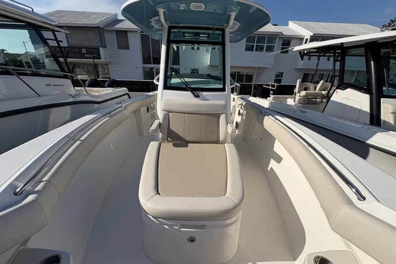 Slide: The Image of 2026 Boston Whaler 280 Outrage boat interior with seating and console, docked outdoors. - 12