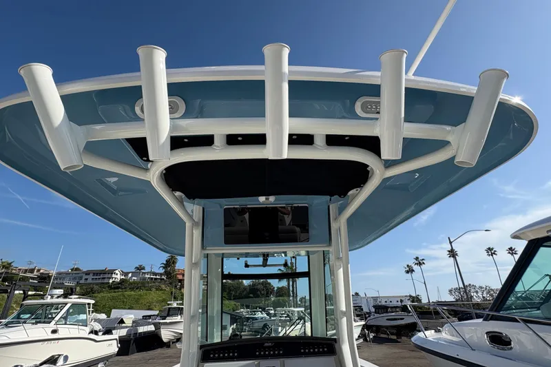 Slide: The Image of 2026 Boston Whaler 280 Outrage boat with rod holders, docked under clear blue sky. - 8