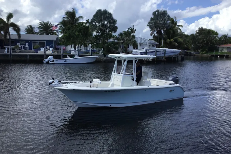 Slide: The Image of 2020 Sea Hunt Ultra 225 boat cruising on a calm waterway near palm trees and houses. - 13