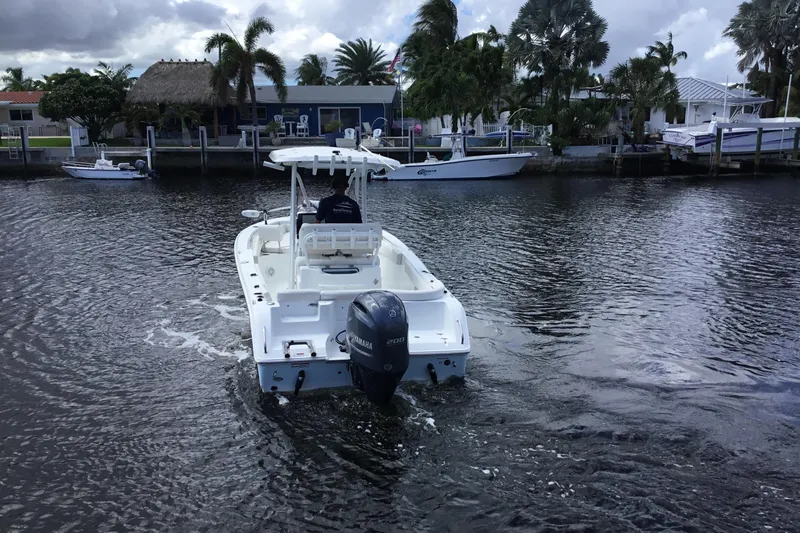 Slide: The Image of 2020 Sea Hunt Ultra 225 boat cruising on a calm waterway near waterfront homes. - 15
