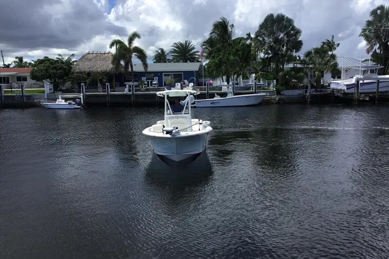 Slide: The Image of 2020 Sea Hunt Ultra 225 boat cruising on a calm canal with palm trees. - 3