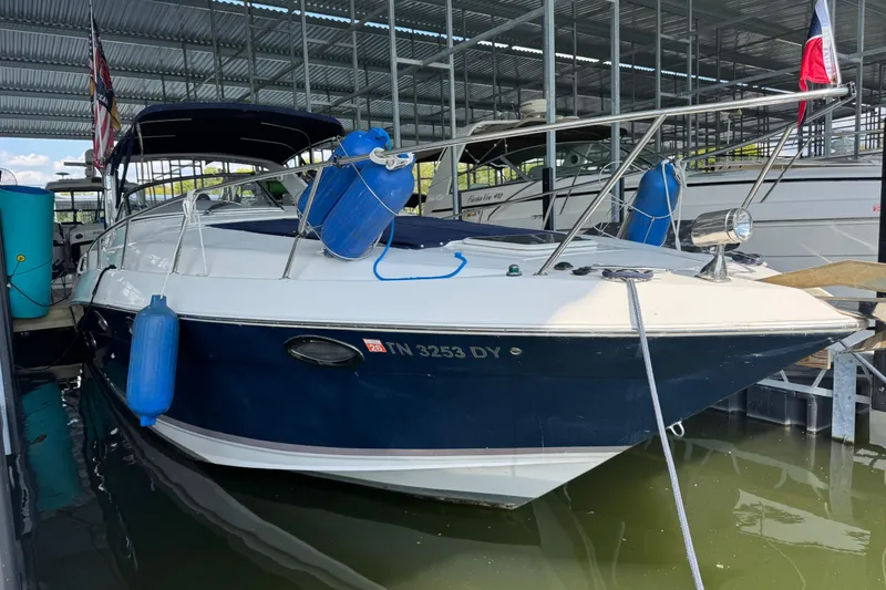 The Image of 2004 Regal Commodore 3260 boat docked, featuring blue fenders and a covered deck. - 0
