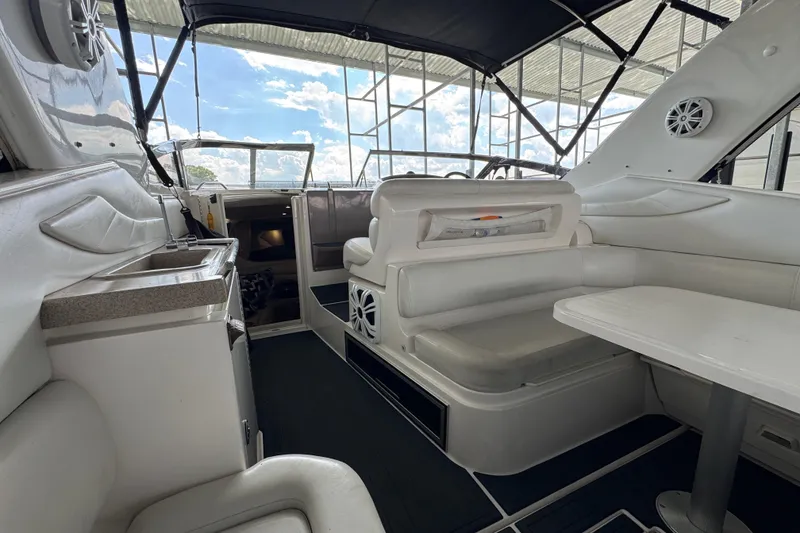 Slide: The Image of 2004 Regal Commodore 3260 interior with white seating, table, and kitchenette under canopy. - 18