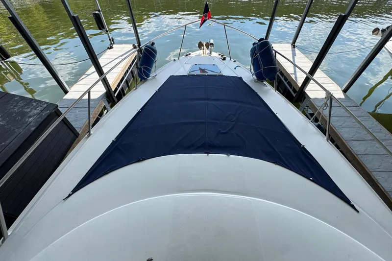 Slide: The Image of 2004 Regal Commodore 3260 boat docked, featuring a blue cover and calm water surroundings. - 9
