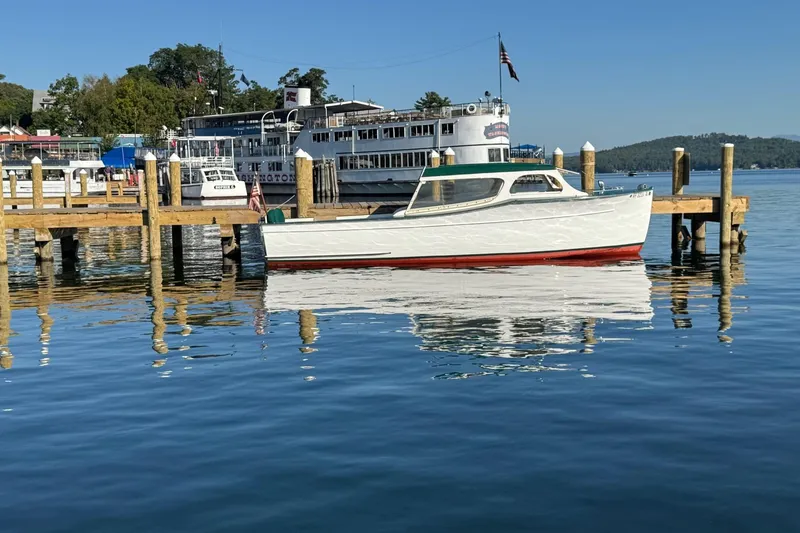 Slide: The Image of 1940 Chris-Craft Launch 25 boat docked on a serene lake with clear blue skies. - 0