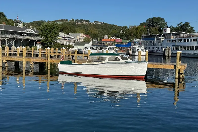 Slide: The Image of 1940 Chris-Craft Launch 25 boat docked at a scenic marina with clear blue water. - 11