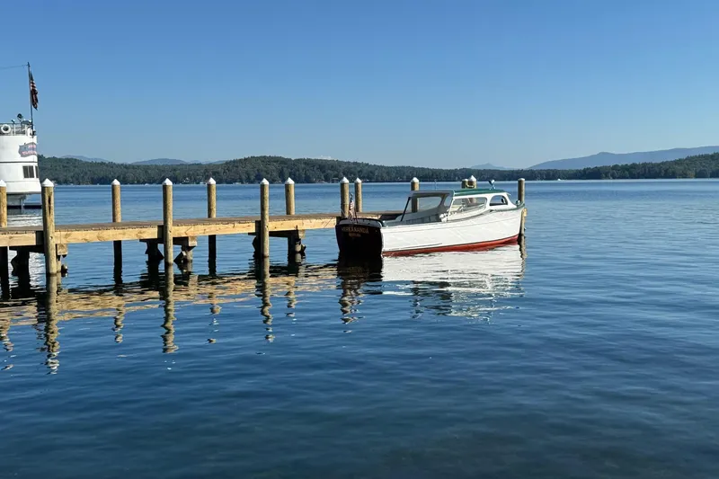 Slide: The Image of 1940 Chris-Craft Launch 25 boat docked on a serene lake under clear blue skies. - 2
