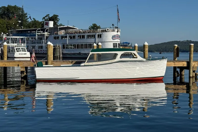 Slide: The Image of 1940 Chris-Craft Launch 25 boat docked on calm water, with a large ship in the background. - 3
