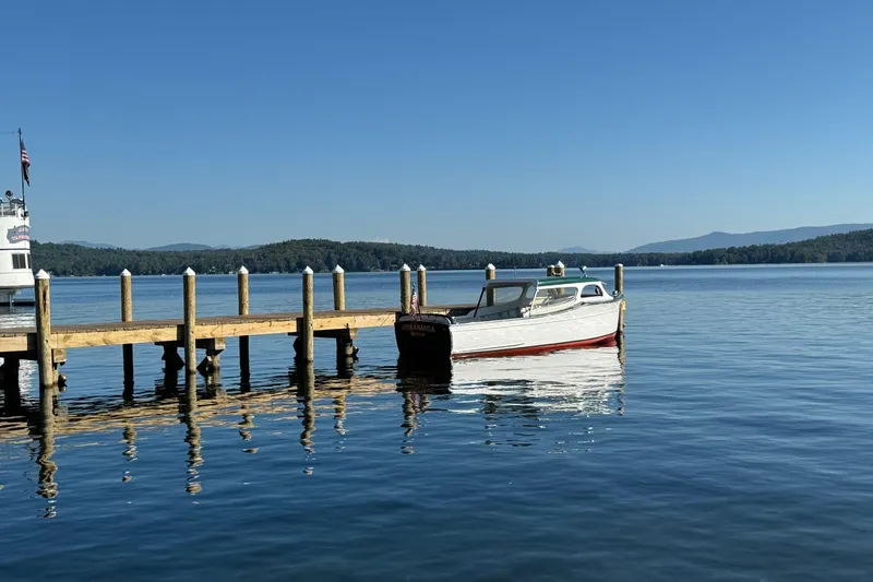 Slide: The Image of 1940 Chris-Craft Launch 25 boat docked on a serene lake with clear blue skies. - 4