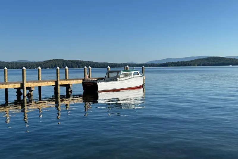 Slide: The Image of 1940 Chris-Craft Launch 25 boat docked on a serene lake with clear blue skies. - 5