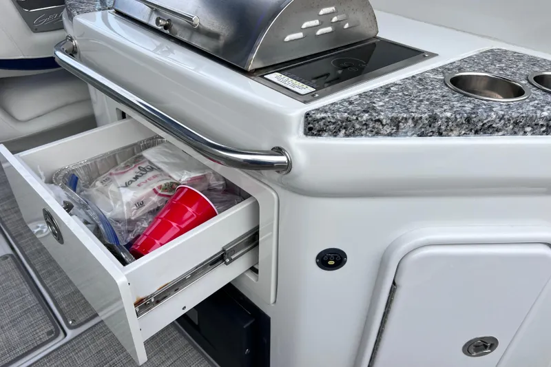 Slide: The Image of Crownline 290 XSS 2022 boat kitchen with grill, drawer, and granite countertop. - 32
