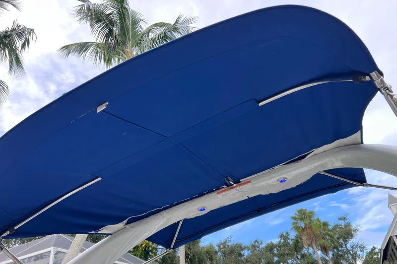 Slide: The Image of Blue canopy of 2022 Crownline 290 XSS boat with palm trees in background. - 34