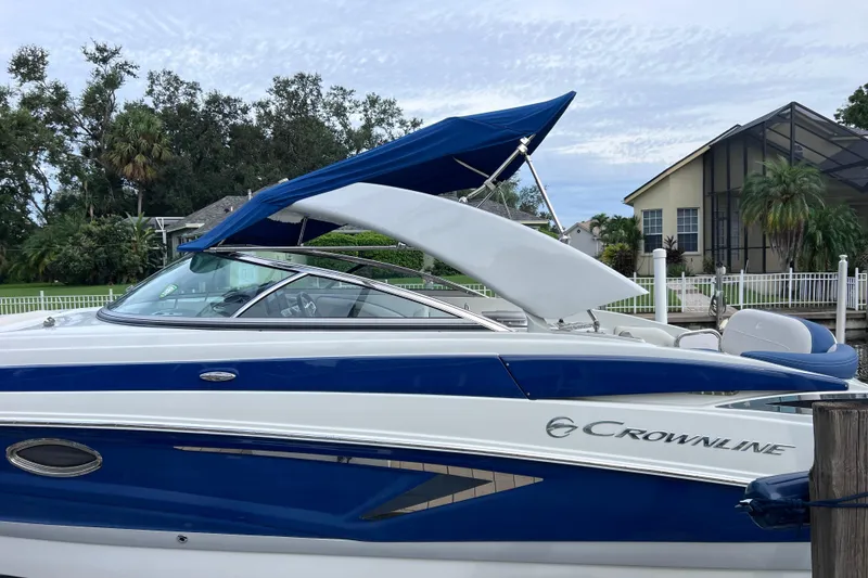 Slide: The Image of 2022 Crownline 290 XSS boat with blue and white design docked near a house. - 59