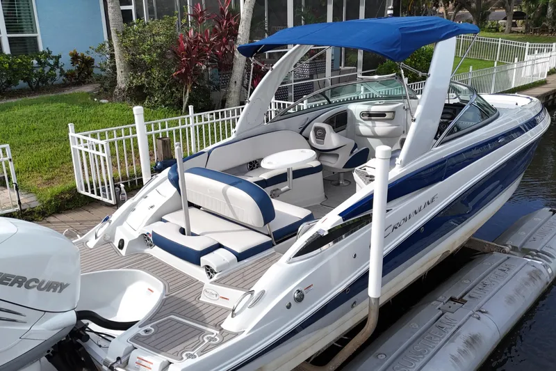 Slide: The Image of 2022 Crownline 290 XSS boat with blue canopy docked by a canal. - 6