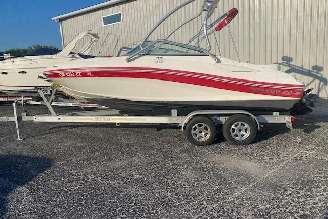 The Image of 2012 Rinker Captiva 216 BR boat on trailer, white with red accents, parked outdoors. - 0