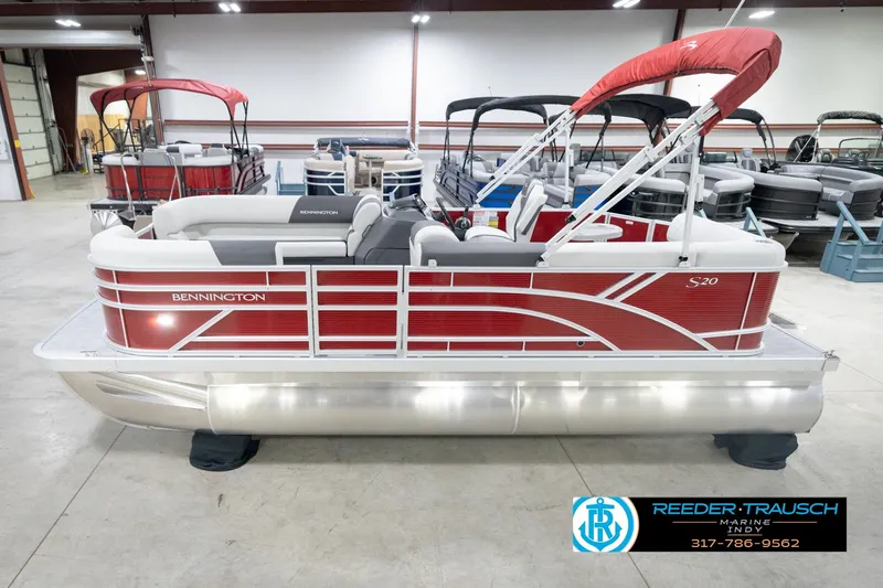 Slide: The Image of 2026 Bennington 20 SL pontoon boat in showroom, featuring red and white design. - 2