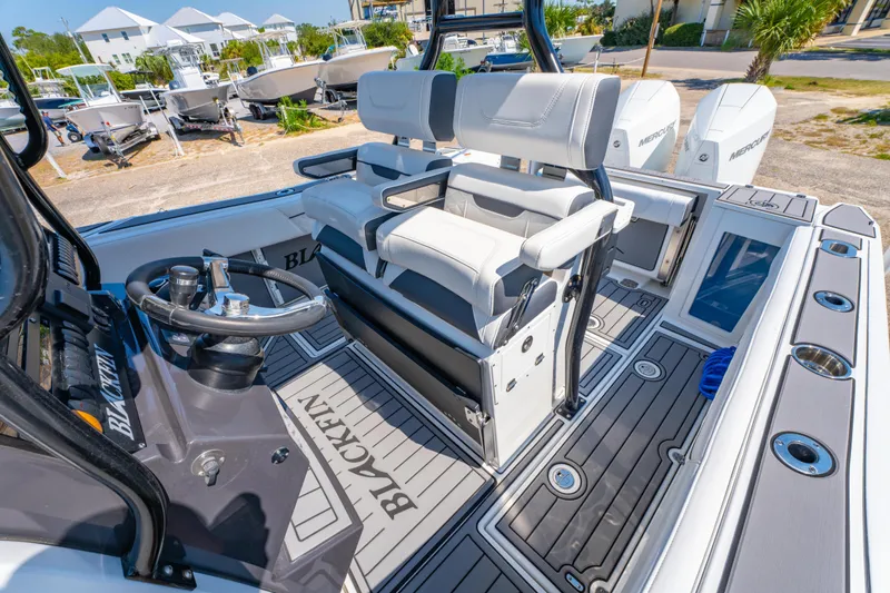 Slide: The Image of 2021 Blackfin 272 CC boat interior with steering wheel and seating, docked outdoors. - 15