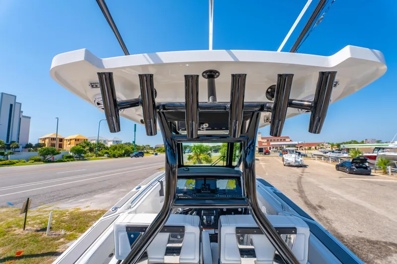 Slide: The Image of 2021 Blackfin 272 CC boat with rod holders, docked near a coastal road. - 21