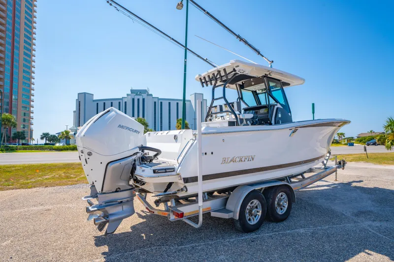 Slide: The Image of 2021 Blackfin 272 CC boat on trailer with Mercury engine, parked near buildings. - 3