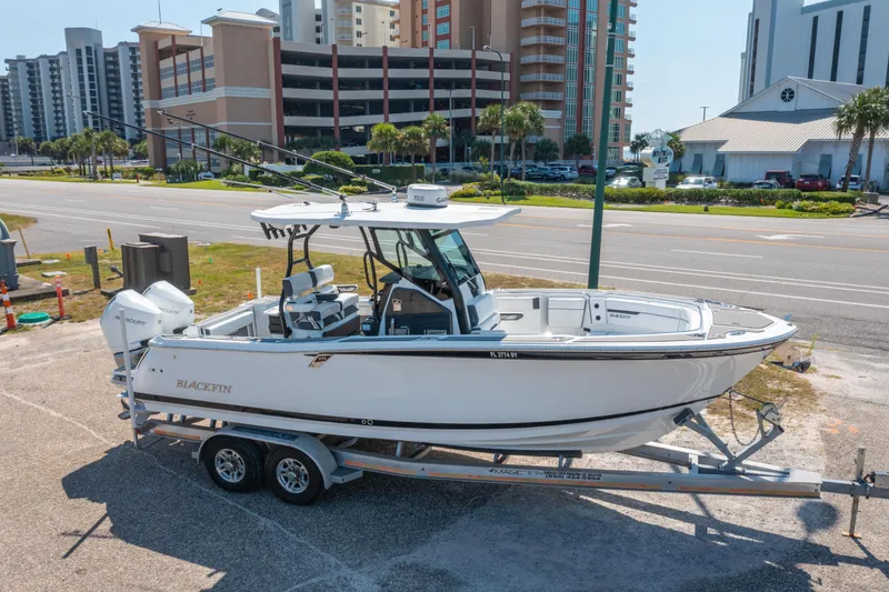 Slide: The Image of 2021 Blackfin 272 CC boat on trailer, parked near coastal buildings. - 31