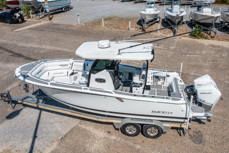 Slide: The Image of 2021 Blackfin 272 CC boat on trailer, featuring dual Mercury engines, parked in a marina. - 32