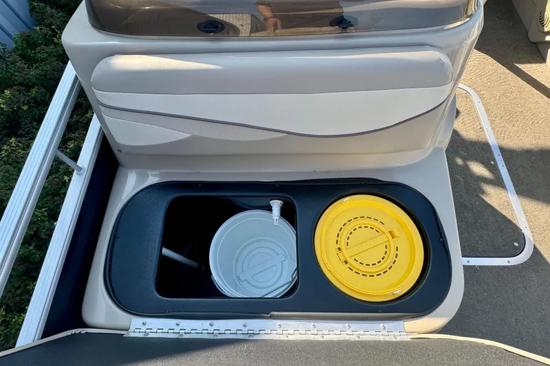 Slide: The Image of 2015 Bennington 24 SFX boat storage compartment with yellow and white containers. - 14