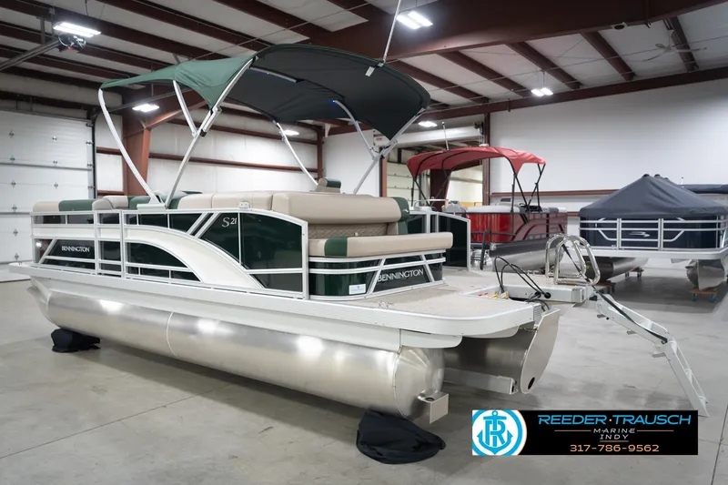 Slide: The Image of 2026 Bennington 20 SLJ pontoon boat in showroom, featuring green canopy and sleek design. - 10