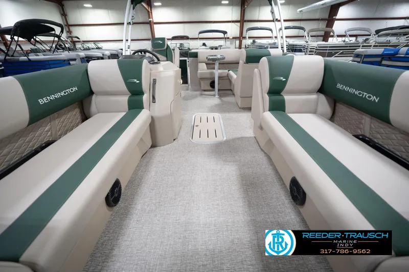 Slide: The Image of 2026 Bennington 20 SLJ pontoon boat interior with green and beige seating in showroom. - 16