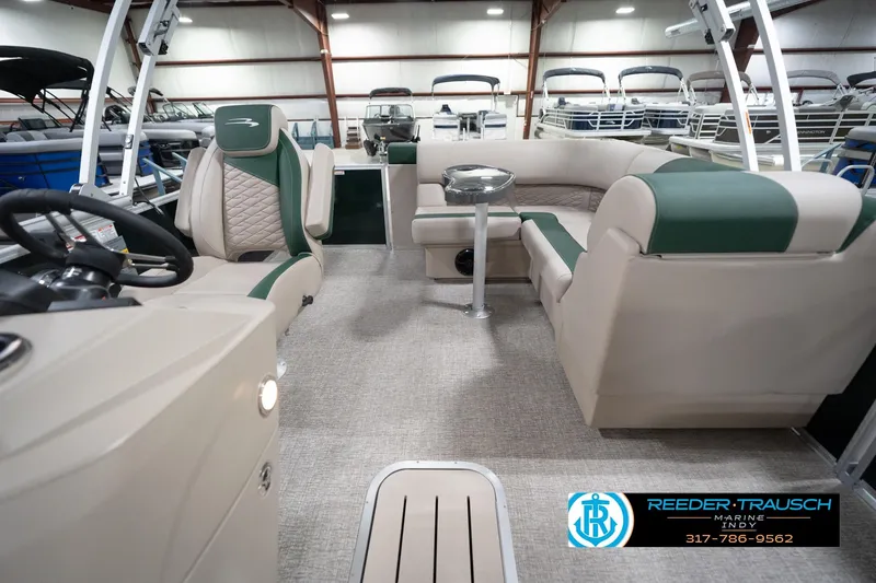 Slide: The Image of 2026 Bennington 20 SLJ pontoon boat interior with green and beige seating, showcased indoors. - 17