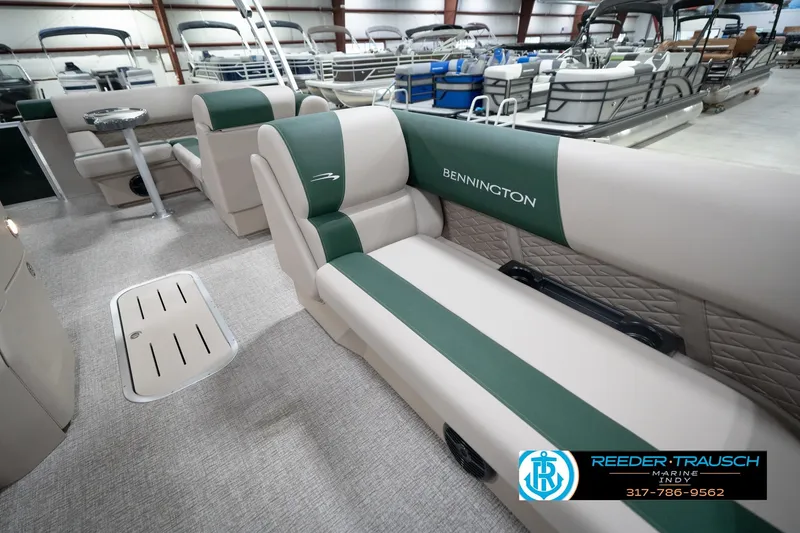 Slide: The Image of 2026 Bennington 20 SLJ pontoon boat interior with green and beige seating in showroom. - 22