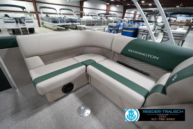 Slide: The Image of 2026 Bennington 20 SLJ pontoon boat interior with beige and green seating in showroom. - 28