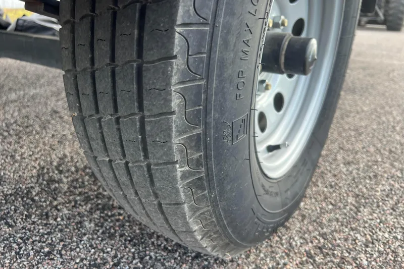 Slide: The Image of Close-up of a 2023 Alumacraft Voyageur 175 SC trailer tire on asphalt. - 10