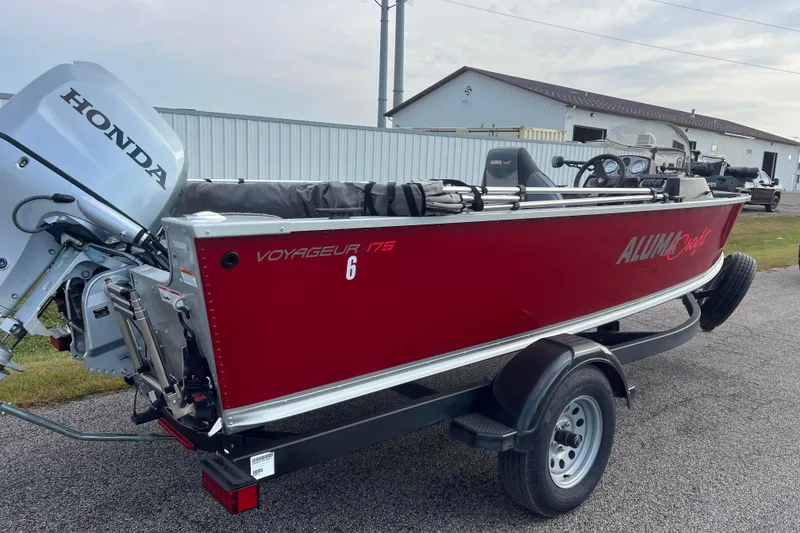 Slide: The Image of 2023 Alumacraft Voyageur 175 SC boat with Honda motor on trailer, red exterior. - 4