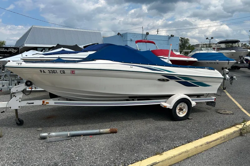 Slide: The Image of 1998 Sea Ray 180 Bow Rider boat on trailer, covered, parked outdoors. - 1