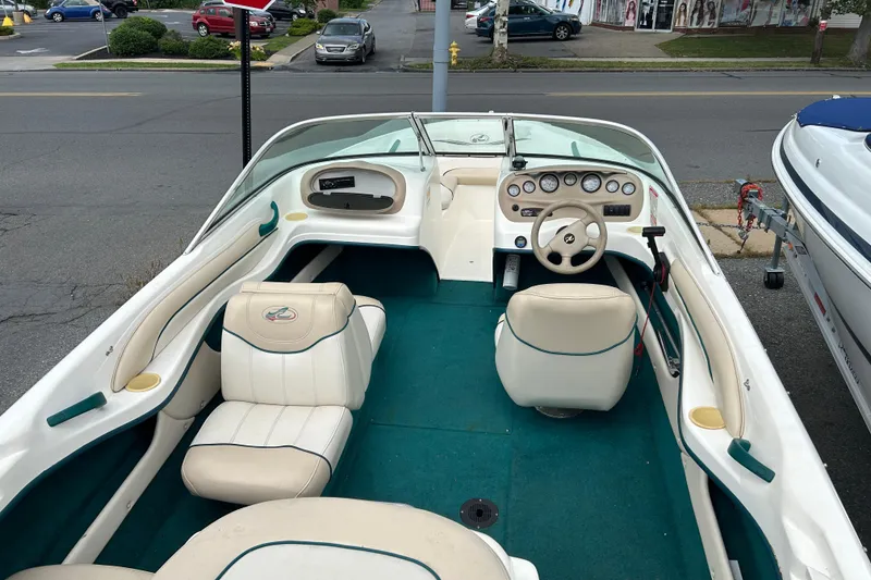 Slide: The Image of 1998 Sea Ray 180 Bow Rider interior with white seats and green carpet, parked on street. - 3