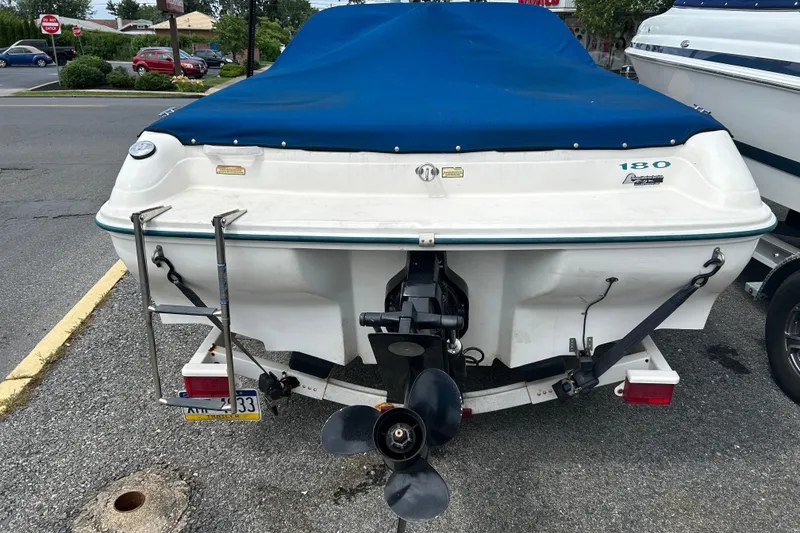 Slide: The Image of 1998 Sea Ray 180 Bow Rider boat with blue cover, parked on a trailer. - 9