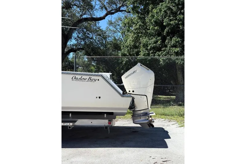 Slide: The Image of 2024 Onslow Bay 33 Tournament boat with Mercury outboard motor, parked near trees. - 3