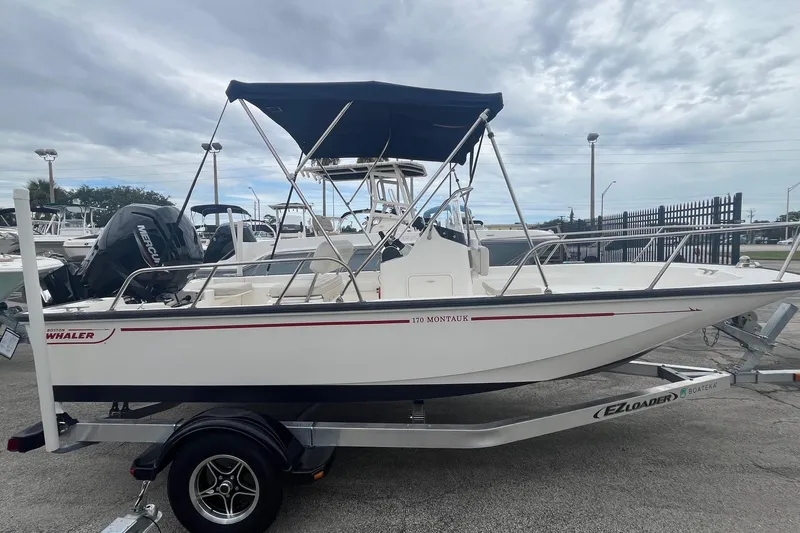 The Image of 2022 Boston Whaler 170 Montauk boat on trailer, with canopy, parked outdoors. - 0