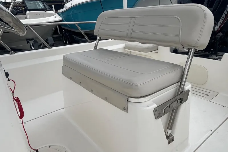Slide: The Image of 2022 Boston Whaler 170 Montauk boat interior with cushioned seating and steering console. - 12
