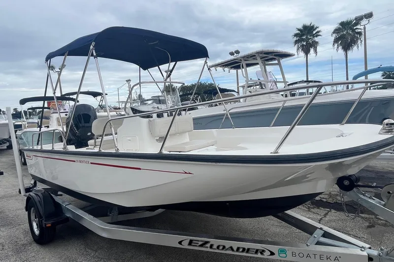 Slide: The Image of 2022 Boston Whaler 170 Montauk boat on trailer, with canopy, parked outdoors. - 4
