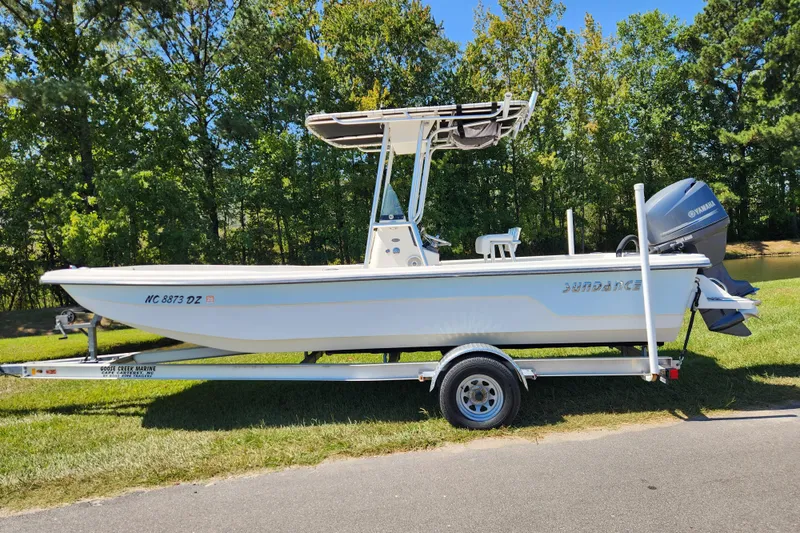 The Image of 2014 Sundance B22CC boat on trailer, parked on grass with trees in background. - 0