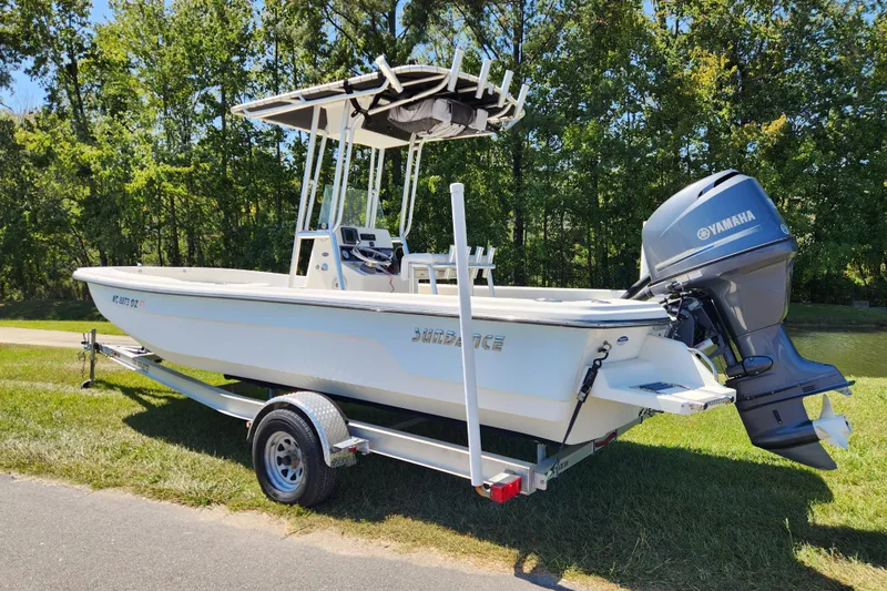 Slide: The Image of 2014 Sundance B22CC boat with Yamaha motor on trailer, parked near trees. - 2