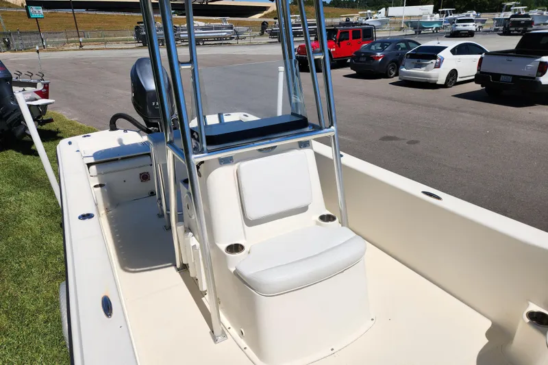 Slide: The Image of 2014 Sundance B22CC boat interior with seating and console, parked in a lot. - 8