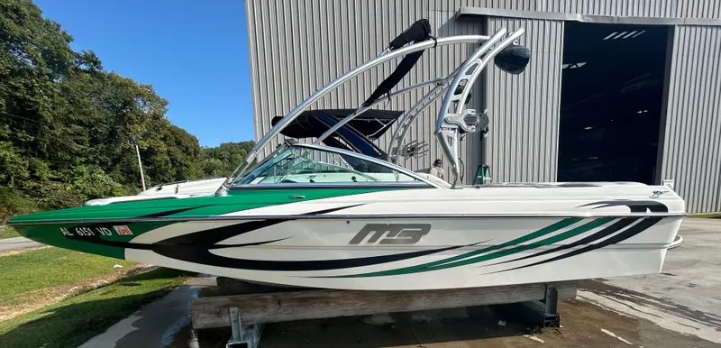 The Image of 2011 MB Sports 21 Tomcat boat with green and black accents, parked outdoors. - 0