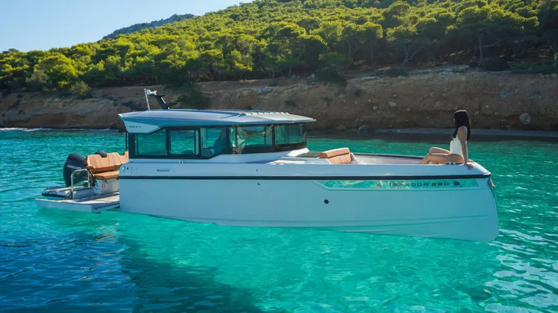 The Image of Saxdor 320 GTC 2025 model boat in clear turquoise water near a forested coastline. - 0